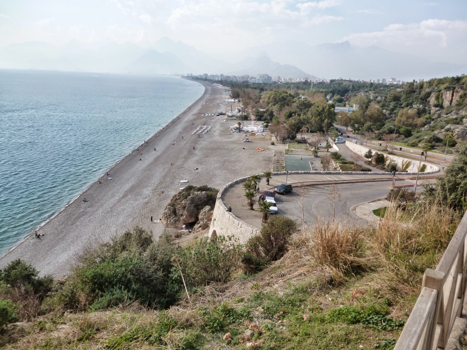 Long pebble beach and calm sea in Antalya seen from a hillside on a hazy November day